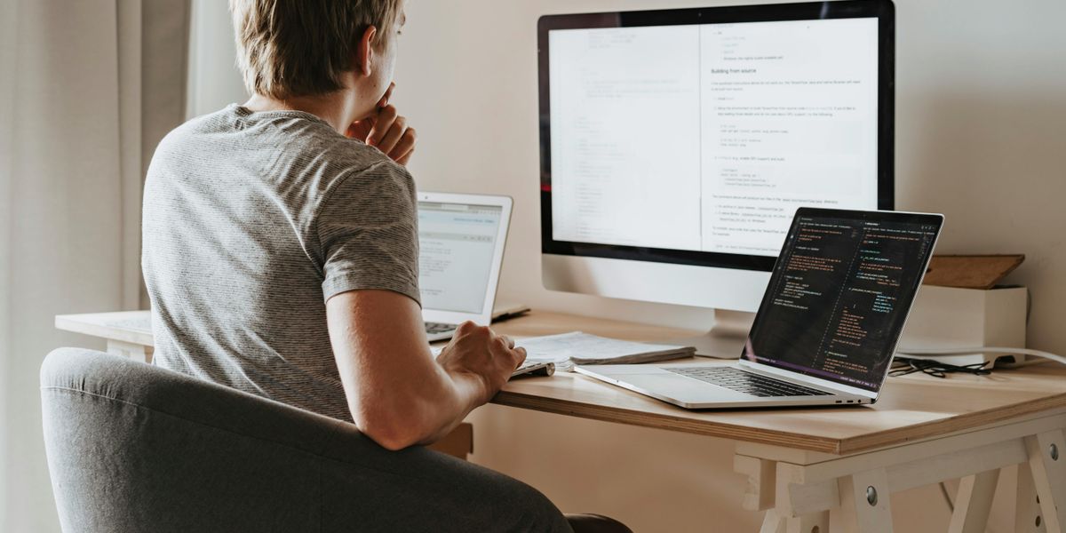 Father programming at home workstation with dual monitors