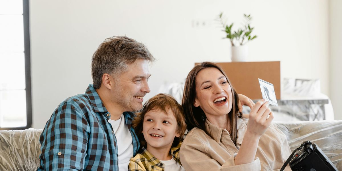 Smiling father working remotely with child playing close by